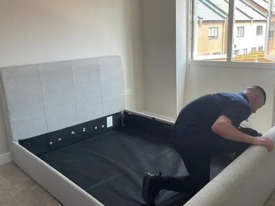 Reliable Removals mover reassembling a double bed frame at a new home