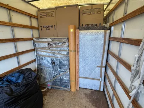 Wardrobe cartons and a wrapped mattress secured inside the removal van