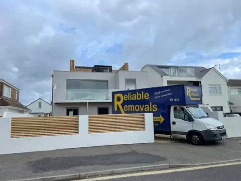 Reliable Removals van outside a modern seafront home