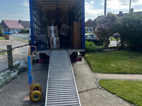 Reliable Removals van with the ramp down, part loaded outside a bungalow