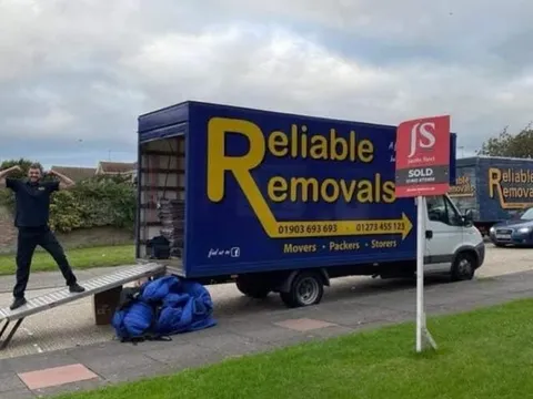 Reliable Removals mover celebrating another completed move outside a sold property